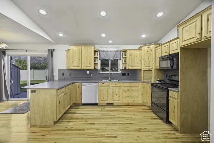 Kitchen featuring wood-finish cabinetry, dark countertops, and stainless steel sink