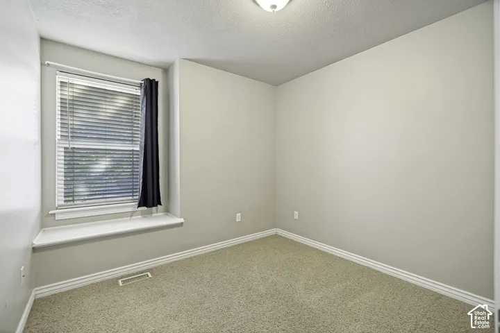 Neutral-toned room featuring a single window with blinds and a built-in window ledge