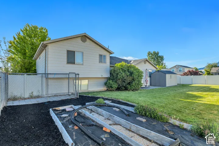 Expansive backyard featuring a manicured lawn, a detached storage shed, and a raised garden bed