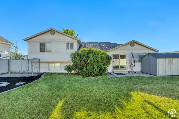 Expansive rear yard featuring a manicured lawn, chain-link fencing, and a concrete patio
