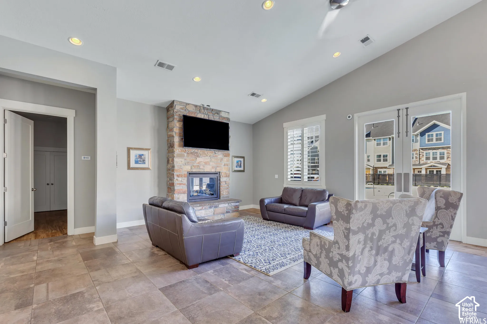 Vaulted ceiling living area featuring a stone-clad fireplace, recessed lighting, and tile flooring