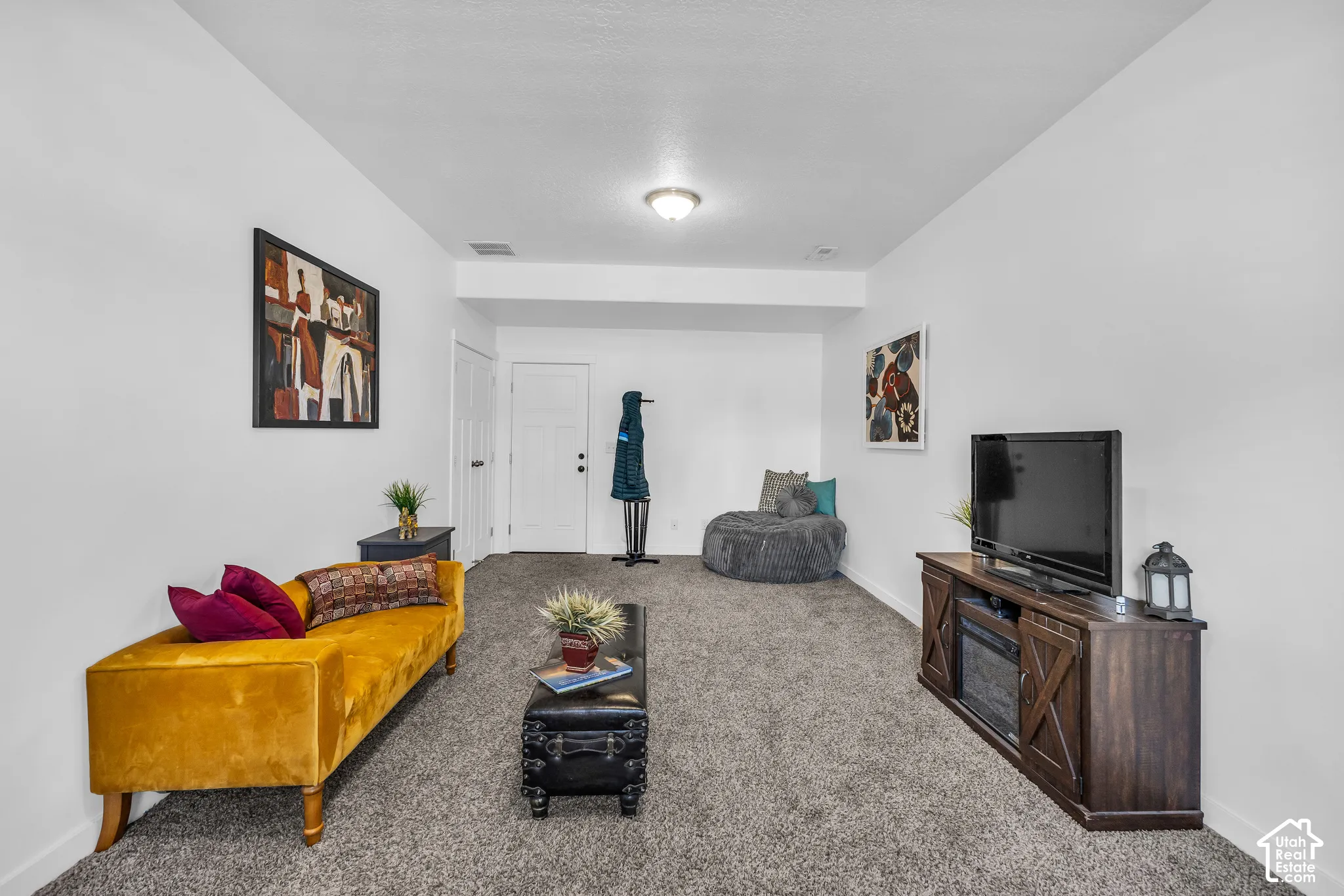 Carpeted living space featuring white walls and a built-in media console with an integrated electric fireplace