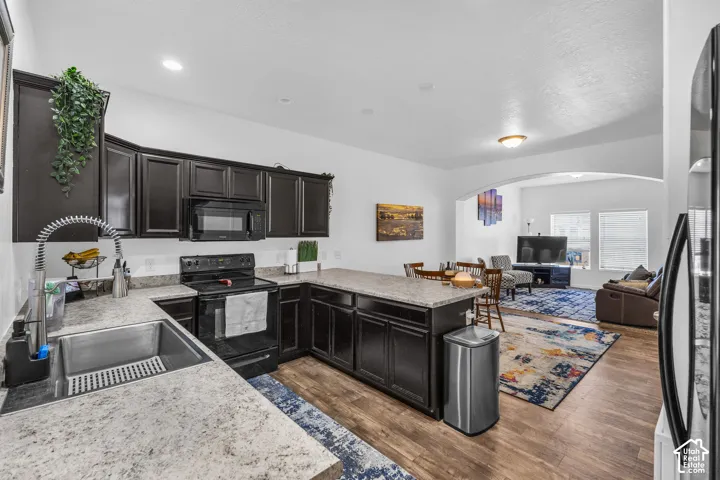 Open-concept kitchen featuring dark cabinetry, light-toned countertops, and wood-finish flooring