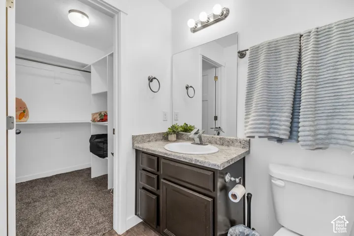 Bathroom vanity featuring a single basin sink, speckled countertop, dark wood-finish cabinetry, and brushed nickel hardware