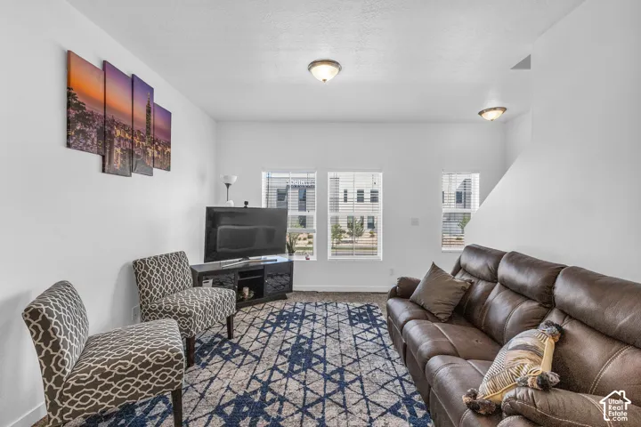 Bright living area featuring white walls, two windows with blinds, and ceiling-mounted light fixtures