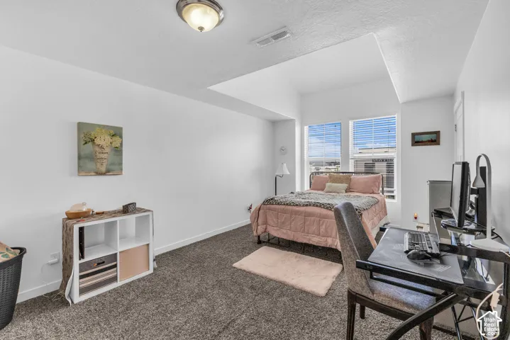 Bedroom featuring textured grey carpeting and white walls