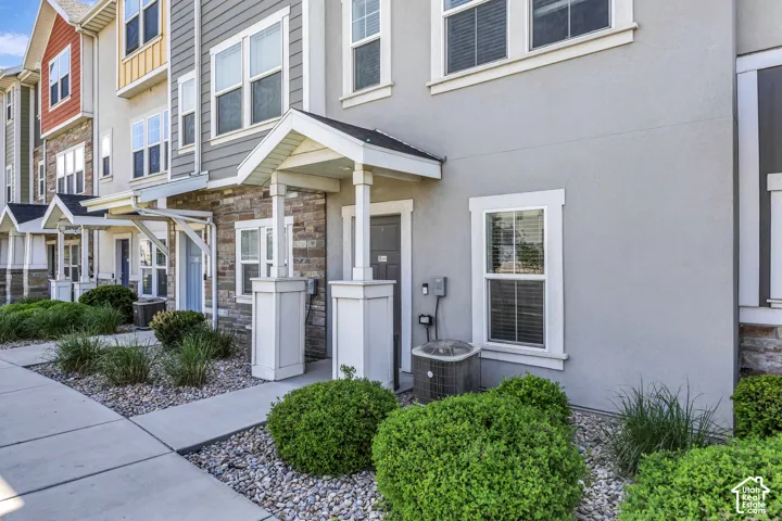 Contemporary townhome exterior featuring a stucco finish, stone accents, covered entry, and individual concrete walkways