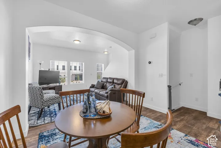Open-concept living space featuring wood-finish flooring, white walls, arched entryway, a built-in thermostat, and recessed lighting