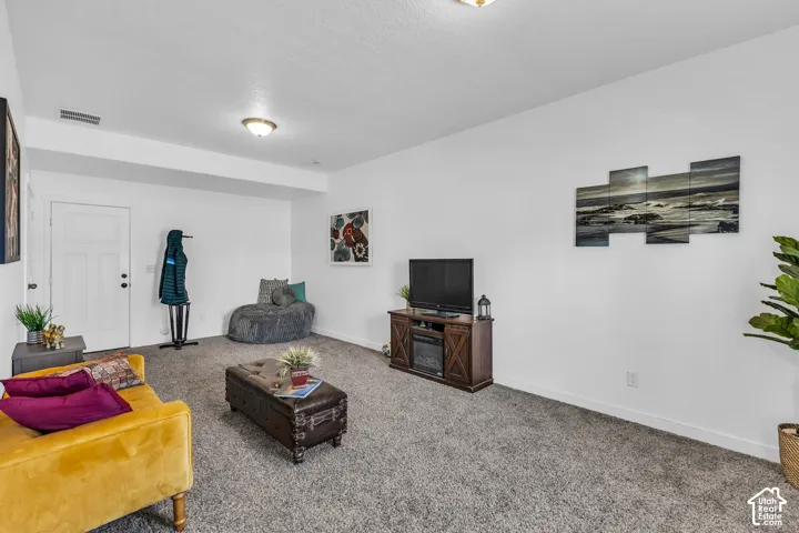Carpeted living area featuring white walls and a built-in wall unit with an electric fireplace
