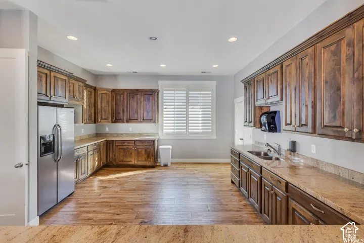 Kitchen featuring extensive wood cabinetry, stone countertops, stainless steel refrigerator, and wood-finish flooring
