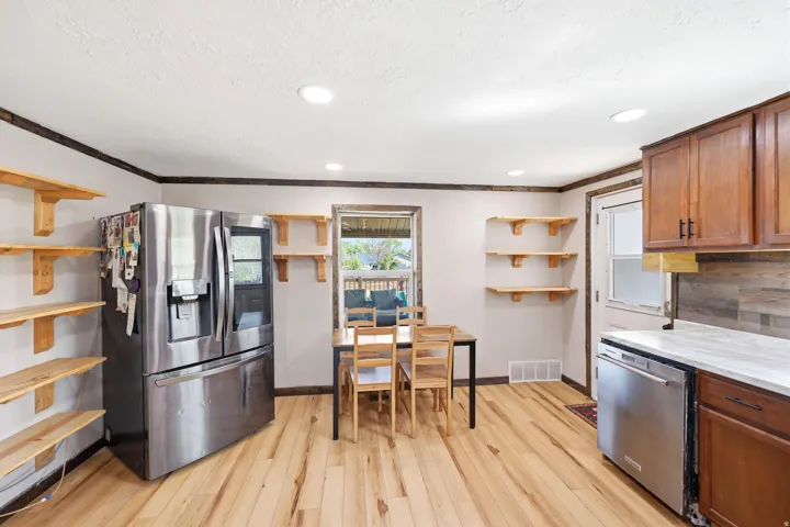 Kitchen with stainless steel appliances, open shelves, plenty of natural light, wood finish cabinets, and a textured ceiling