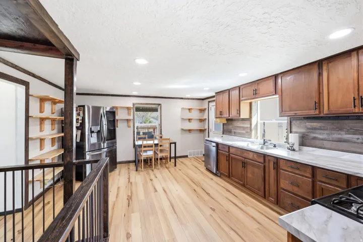 Kitchen featuring light countertops, light wood-style flooring, wood finish cabinets, backsplash, and recessed lighting