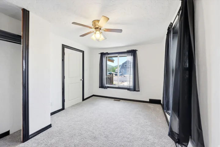 Unfurnished bedroom with light colored carpet, ceiling fan, and a textured ceiling