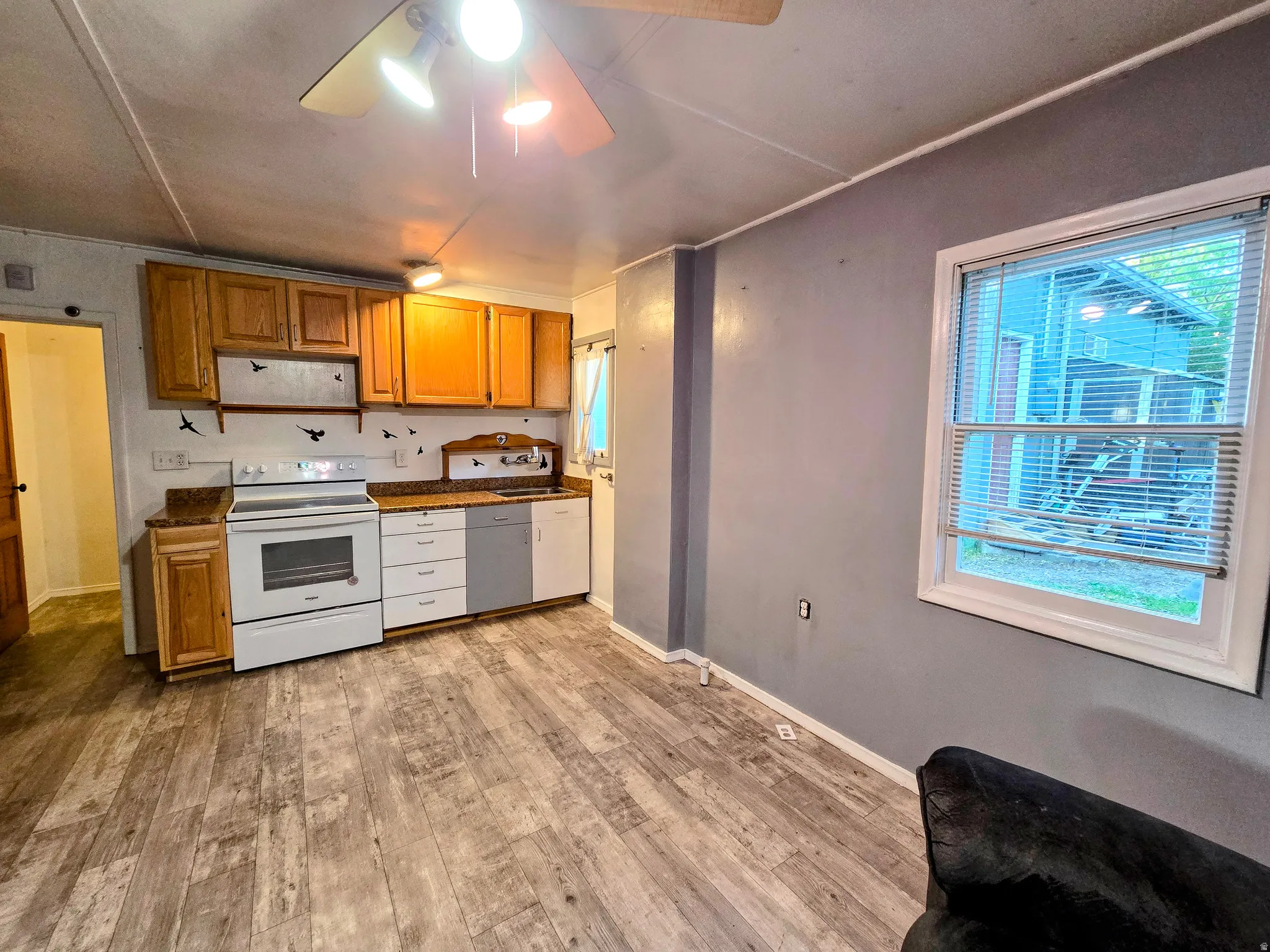 Kitchen area featuring wood-finish flooring, wood cabinetry, stone-look countertops, and white appliances