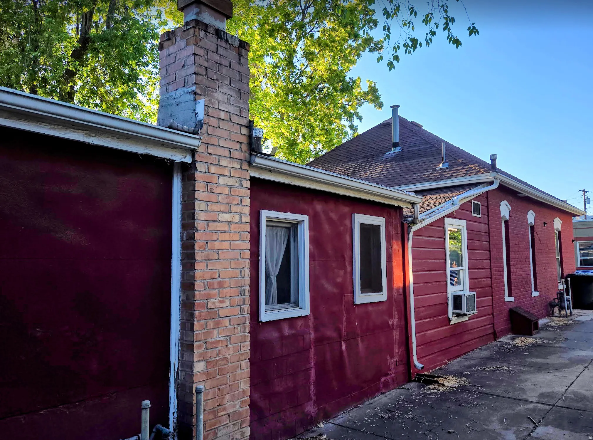 Exterior featuring a brick chimney, red siding, and white window trim