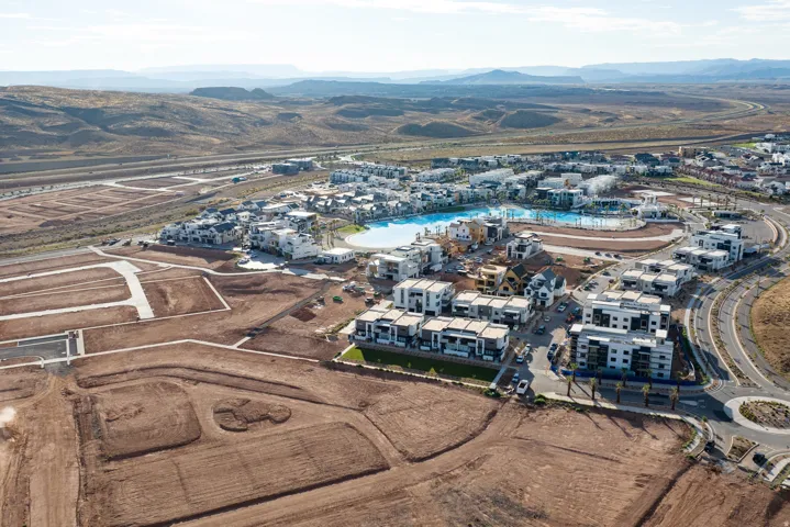 Sprawling community development featuring residential structures, a large central lagoon, a circular roadway, and multiple building pads