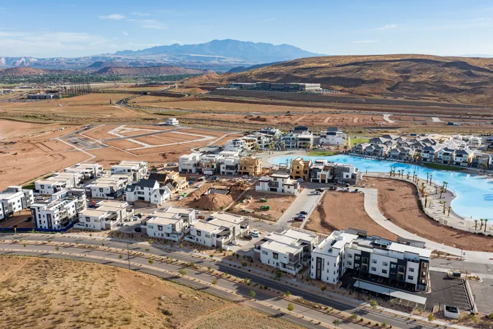 Expansive development featuring a large lagoon, contemporary architecture, mountain backdrop, and multiple building styles
