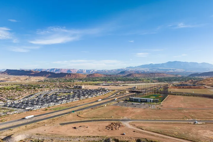 Expansive desert landscape featuring a residential development, a multi-lane highway, and a golf driving range