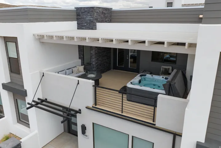 Expansive private patio featuring a built-in spa, pergola, black slate accent wall, and stucco finishes