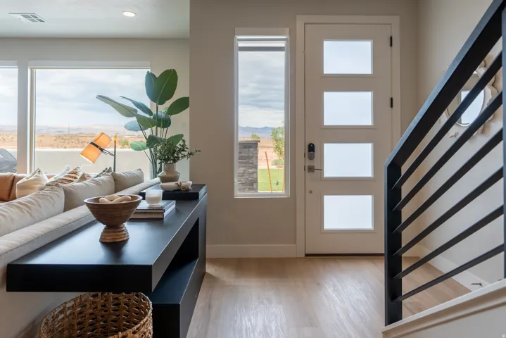 Entryway featuring a modern front door with frosted glass inserts, light wood-finish flooring, and a contemporary black metal stair railing