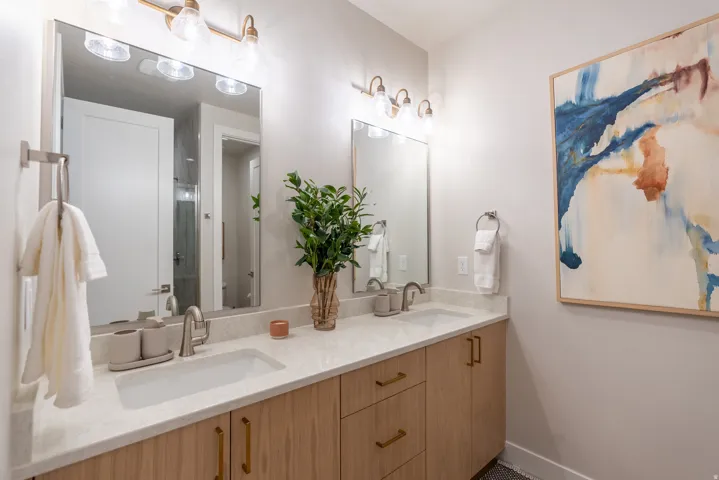 Dual vanity with light wood-finish cabinetry and gold-tone hardware