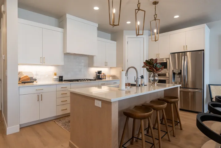 Modern kitchen featuring white cabinetry, stainless steel appliances, a center island with bar seating, wood-finish flooring, and pendant lighting