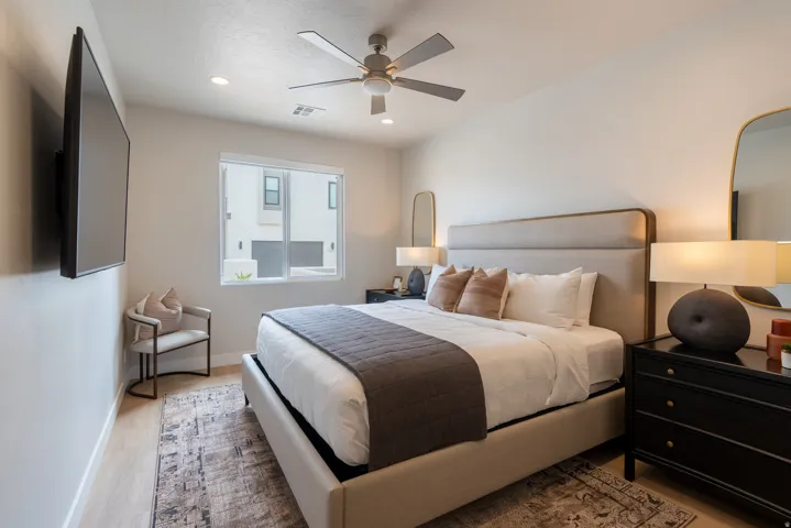 Bright bedroom featuring light wood-finish flooring, recessed ceiling lights, and a ceiling fan with light fixture
