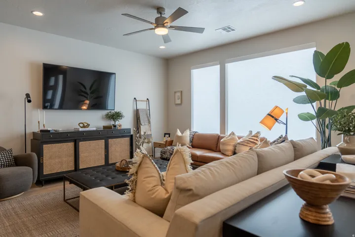 Spacious living area featuring a ceiling fan, recessed lighting, large windows, and neutral wall tones