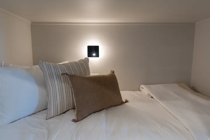 Recessed sleeping area with a contemporary wall-mounted light fixture and light-colored walls