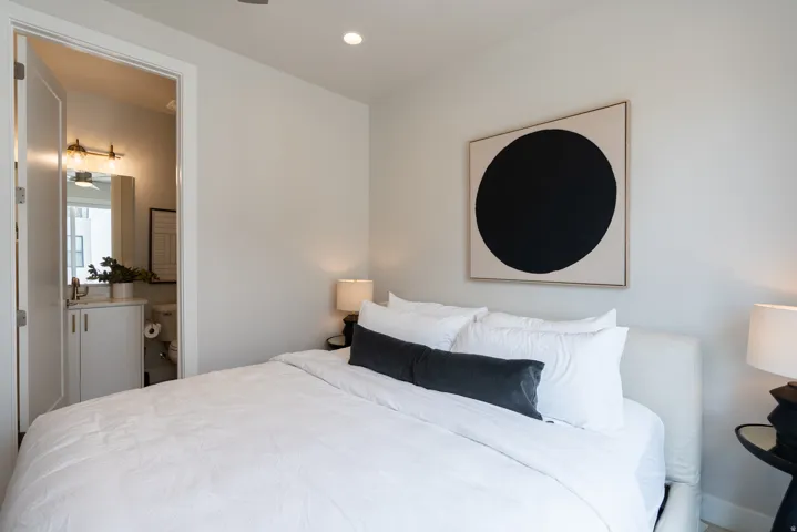 Bedroom with light neutral walls, recessed lighting, and an attached bathroom