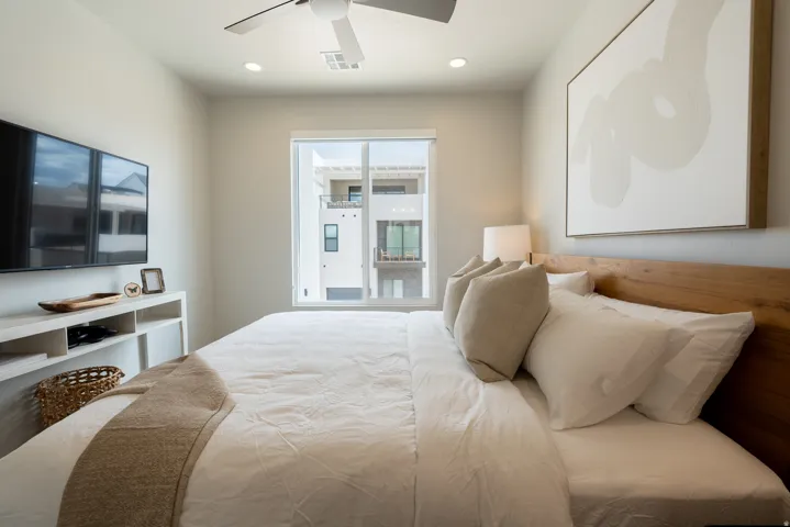 Bedroom featuring a contemporary ceiling fan, recessed lighting, a large window, a built-in media console, and a wood-finish headboard