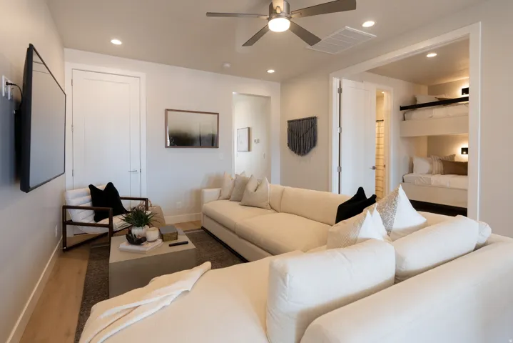 Spacious living area featuring light wood-finish flooring, recessed lighting, and a modern ceiling fan
