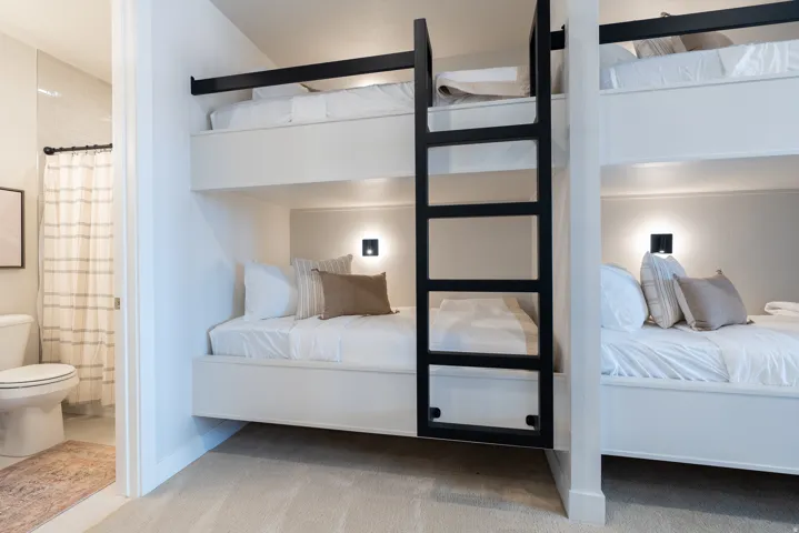 Built-in bunk beds featuring matte black ladders and individual wall-mounted sconces