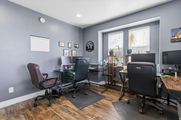 Dedicated workspace featuring wood-finish flooring, neutral wall tones, and recessed lighting