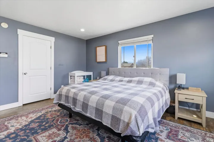 Spacious room featuring wood-finish flooring, a contemporary window, recessed ceiling lighting, and a solid core door with white trim