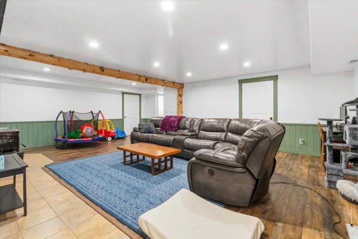 Spacious room featuring wood-finish flooring, recessed lighting, and exposed wood beam accents