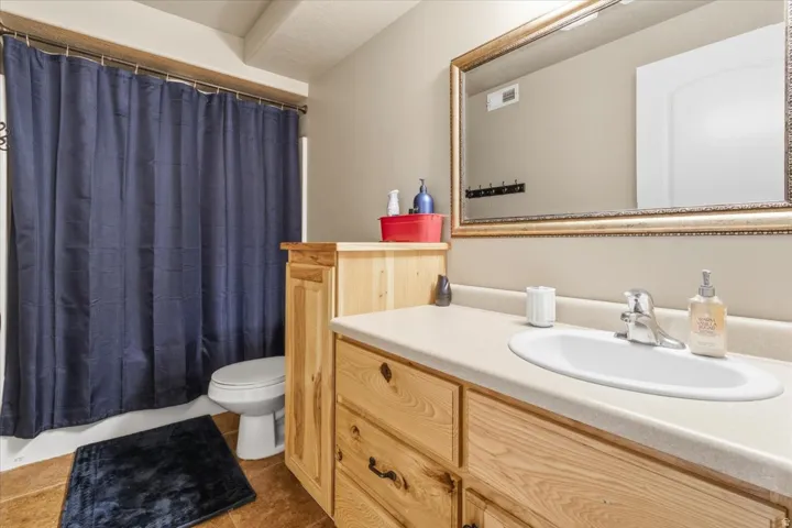 Bathroom featuring a wood-finish vanity with an integrated sink and light-colored countertop