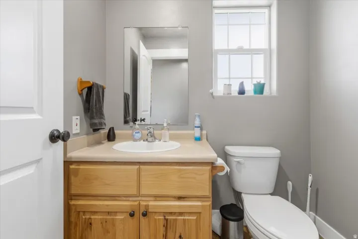 Bathroom with a natural wood-finish vanity, integrated sink, and light-toned countertop