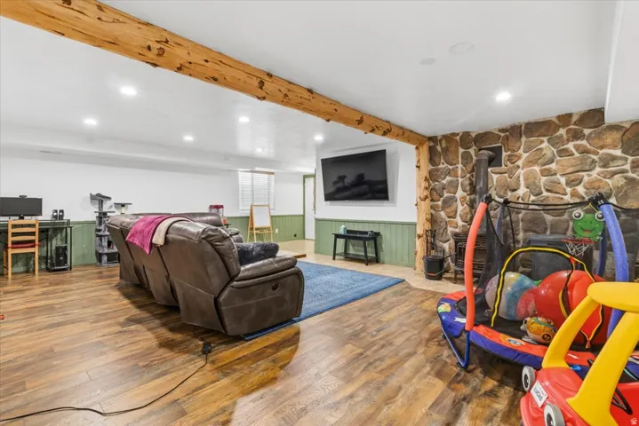 Finished interior space featuring wood-finish flooring, a stone accent wall, and a rustic exposed beam