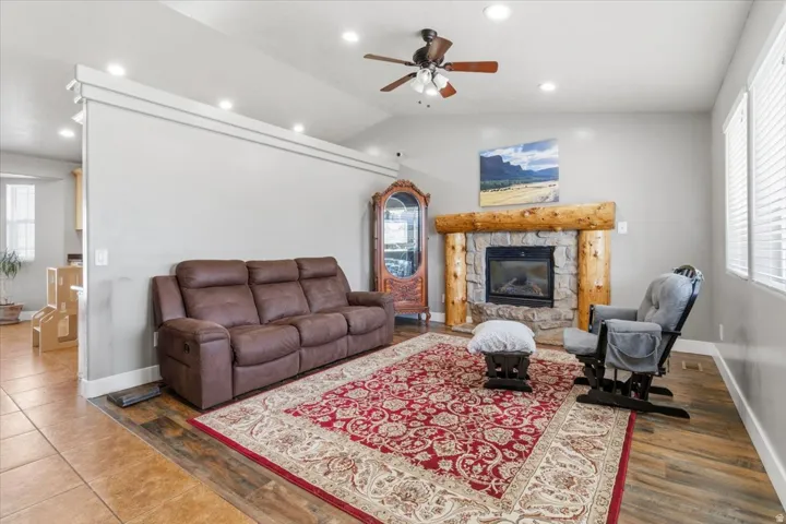Living area featuring a stone-clad fireplace with a log mantel, wood-finish flooring, and recessed lighting