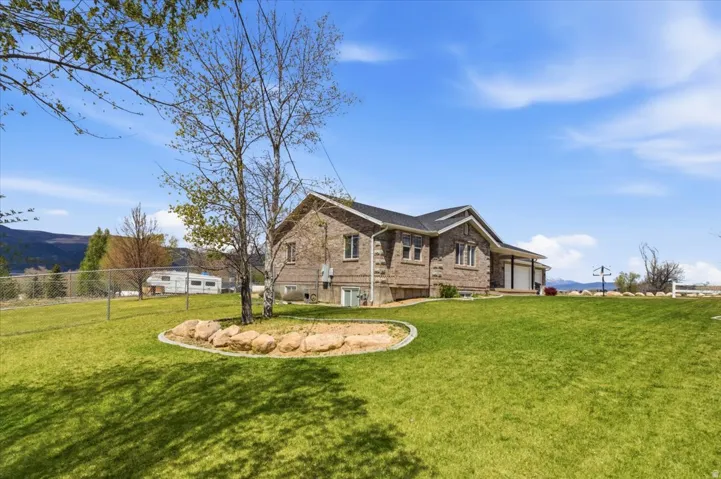 Expansive green lawn with a rock-bordered landscape bed and mature trees