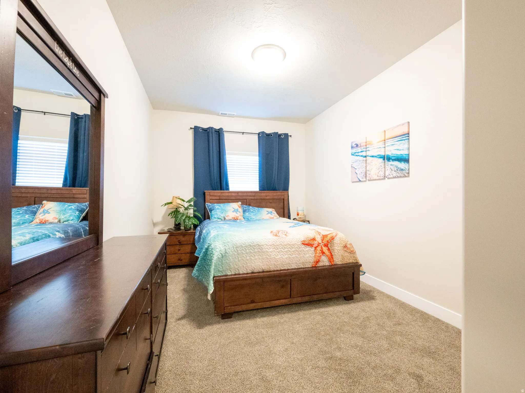 Bright sleeping space featuring neutral wall tones, textured carpeting, and a semi-flush mount ceiling light