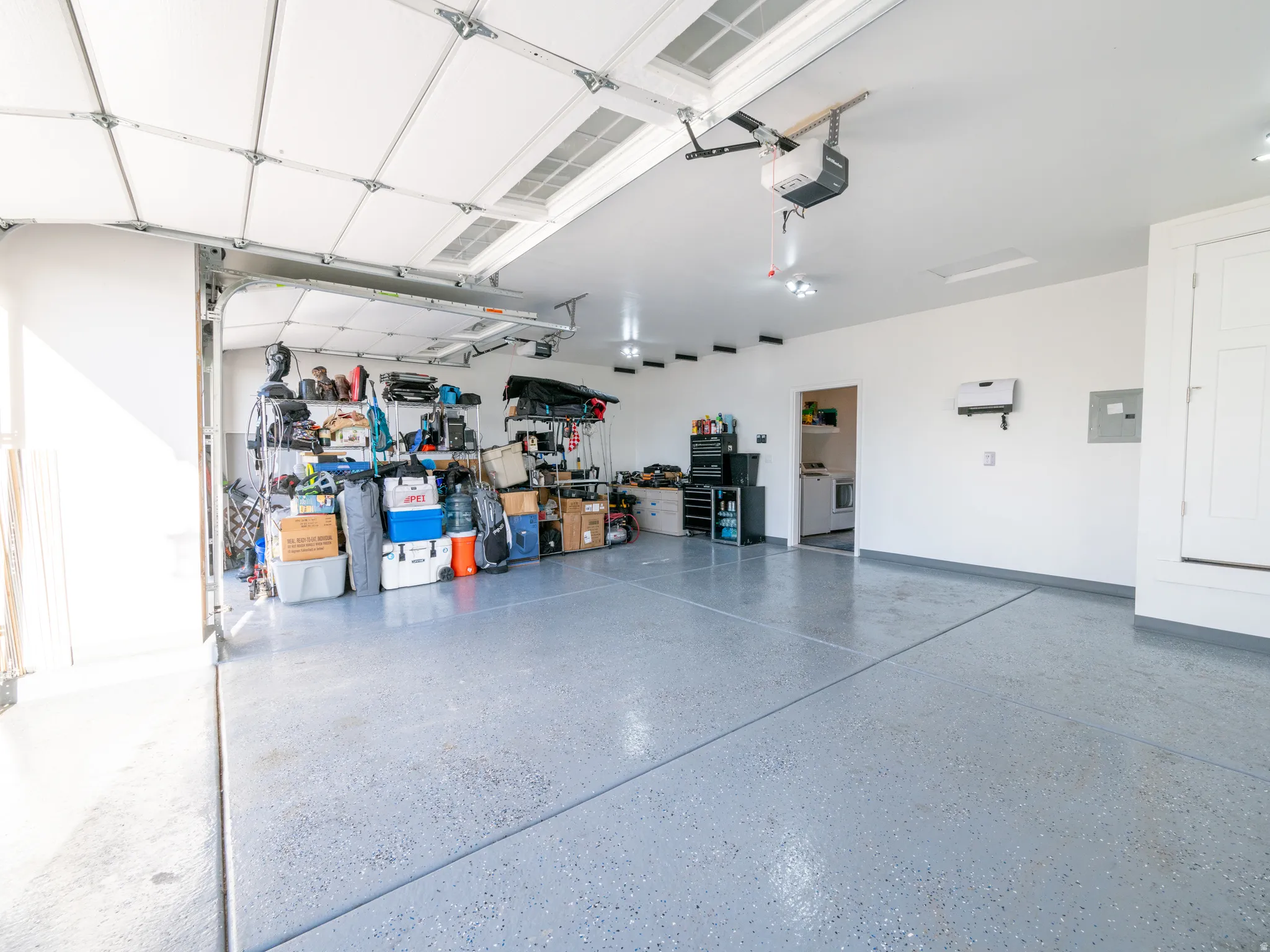 Spacious garage featuring a durable epoxy-coated floor, painted walls, and an automated garage door opener