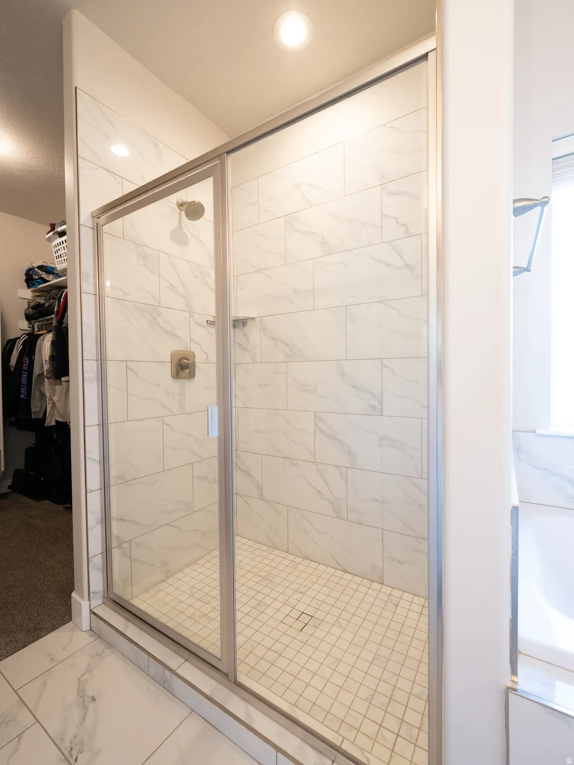 Walk-in shower with clear glass enclosure and brushed nickel fixtures