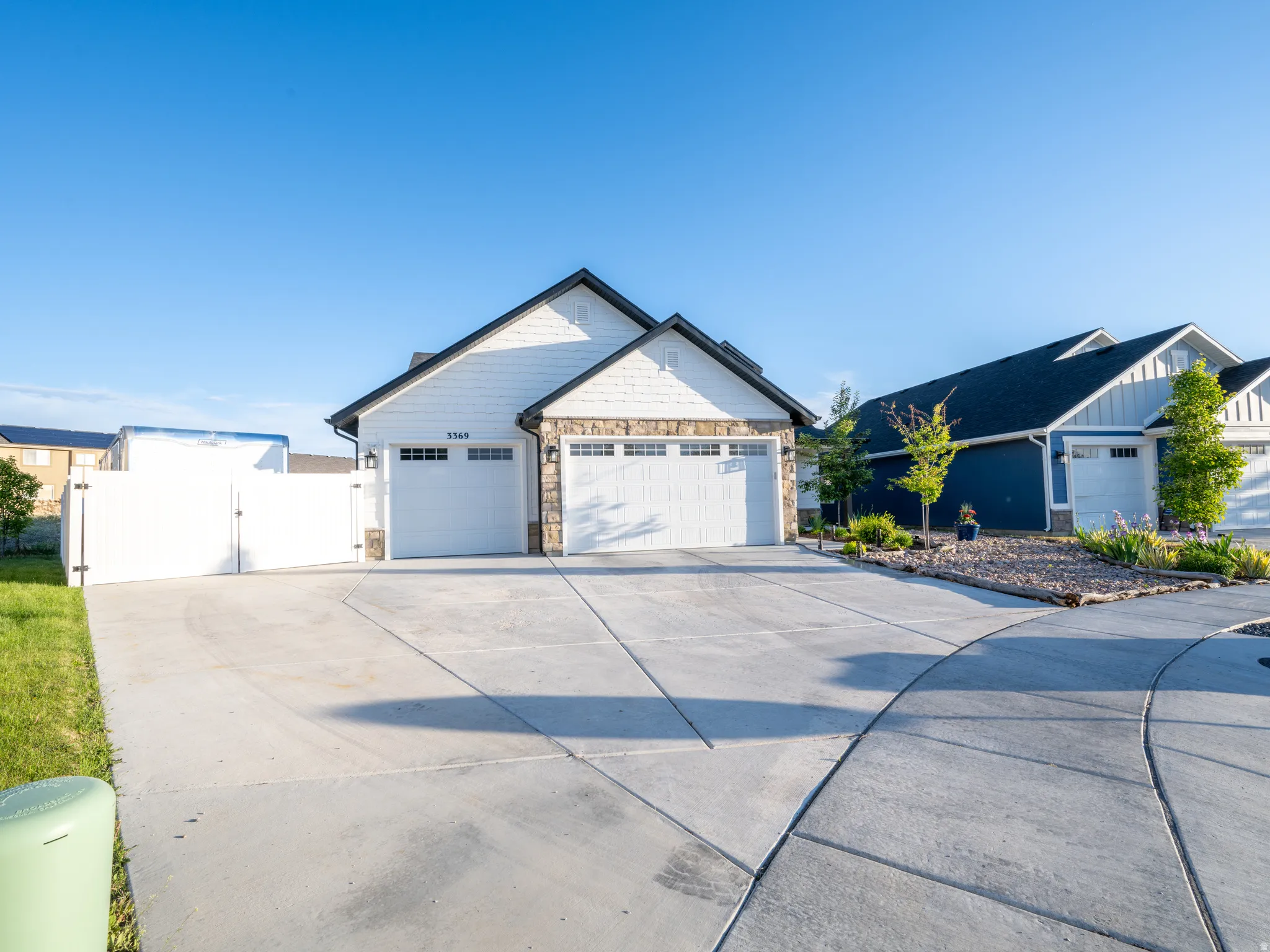 Front exterior of a single-story residence featuring white siding and stone accents