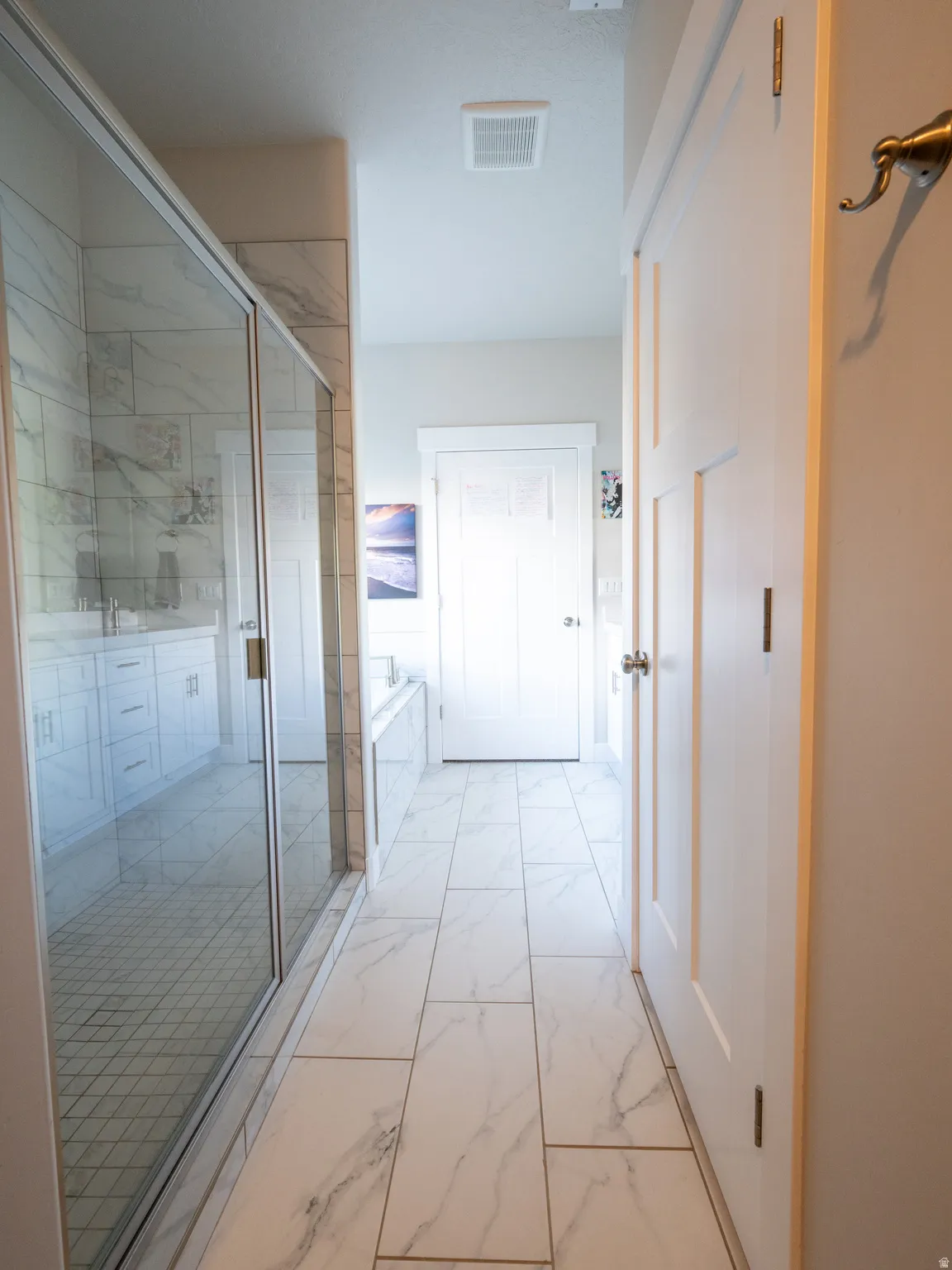 Spacious bathroom featuring large format marble-look floor tiles, a clear glass enclosed shower, and a built-in soaking tub