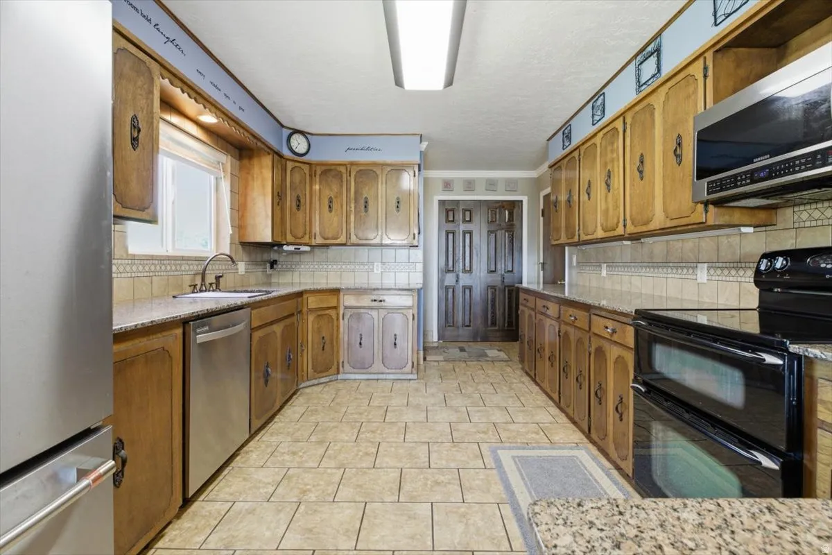 Spacious kitchen featuring extensive wood cabinetry, tile flooring, granite-look countertops, stainless steel appliances, and a double oven range
