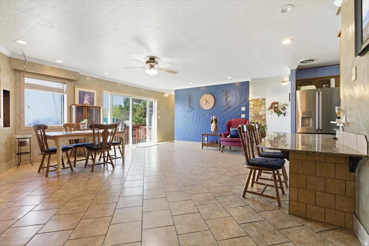 Spacious open-concept living area featuring tile flooring, recessed lighting, and a ceiling fan