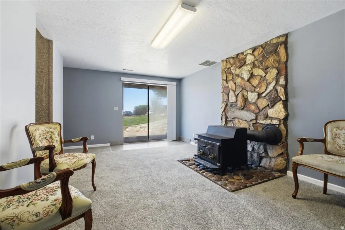 Living area featuring a stone accent wall, wood-burning stove, and sliding glass doors