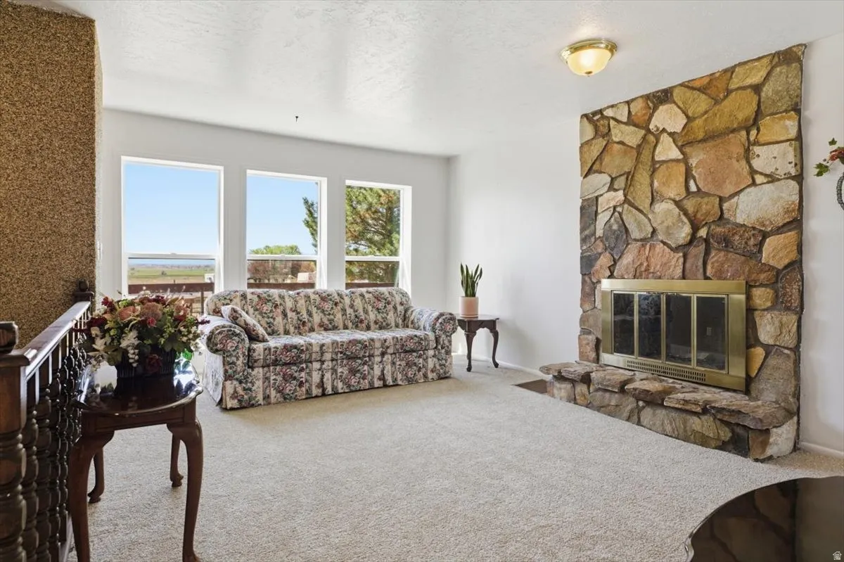 Spacious living area featuring a floor-to-ceiling stone fireplace with a brass-framed firebox, large windows, and a textured accent wall